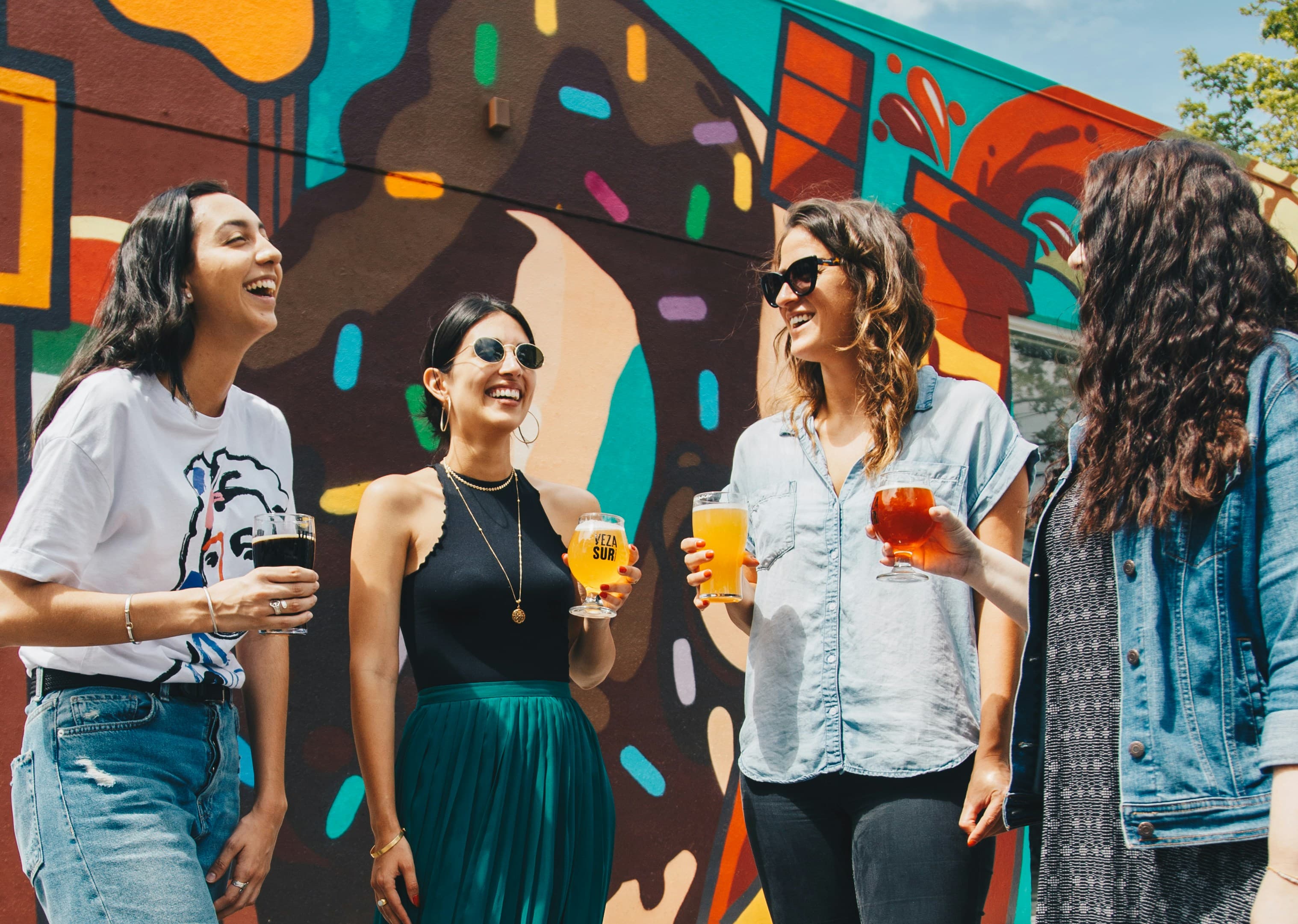 Friends raising their glasses in front of a colorful mural