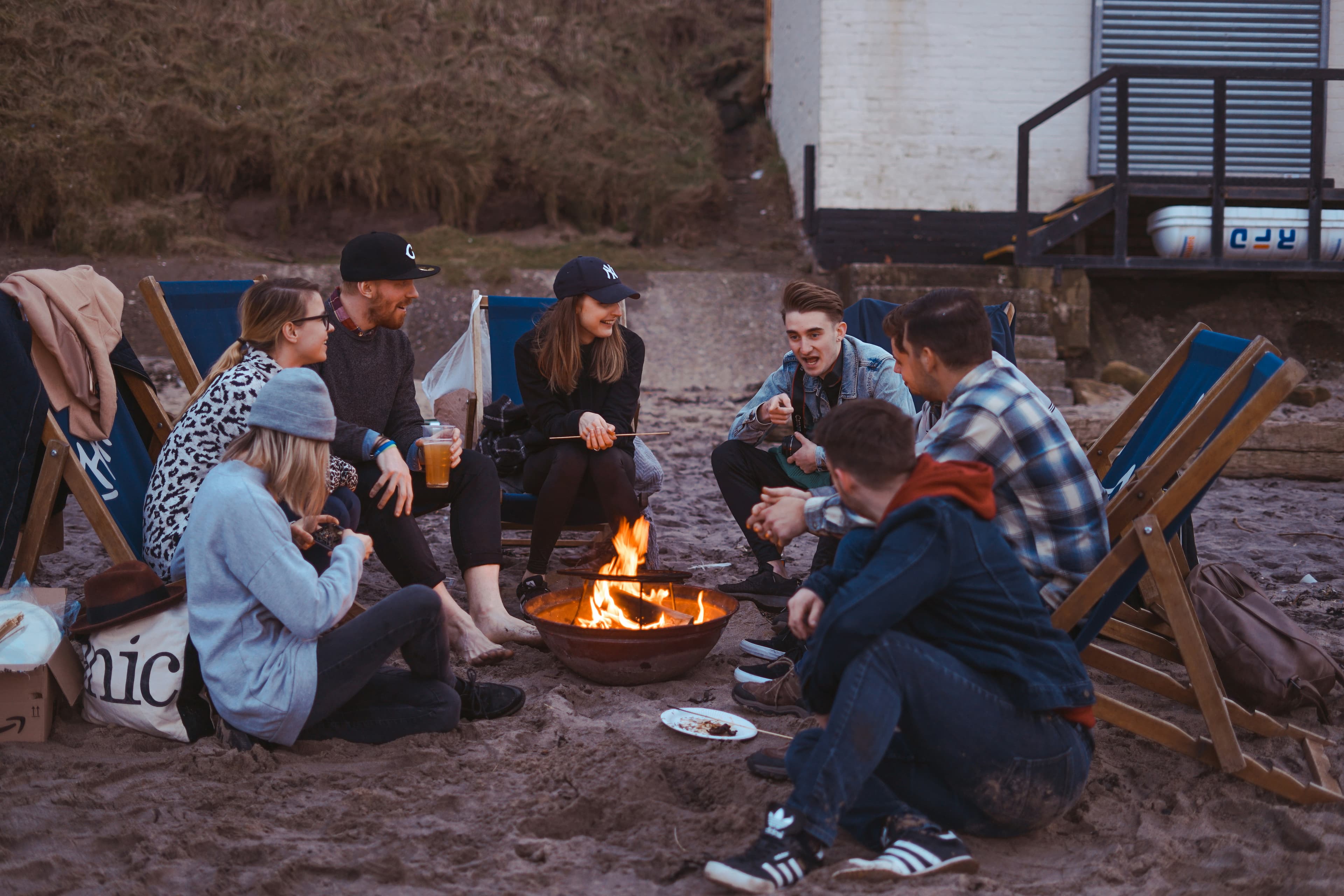 A group of friends gathered around an outdoor campfire