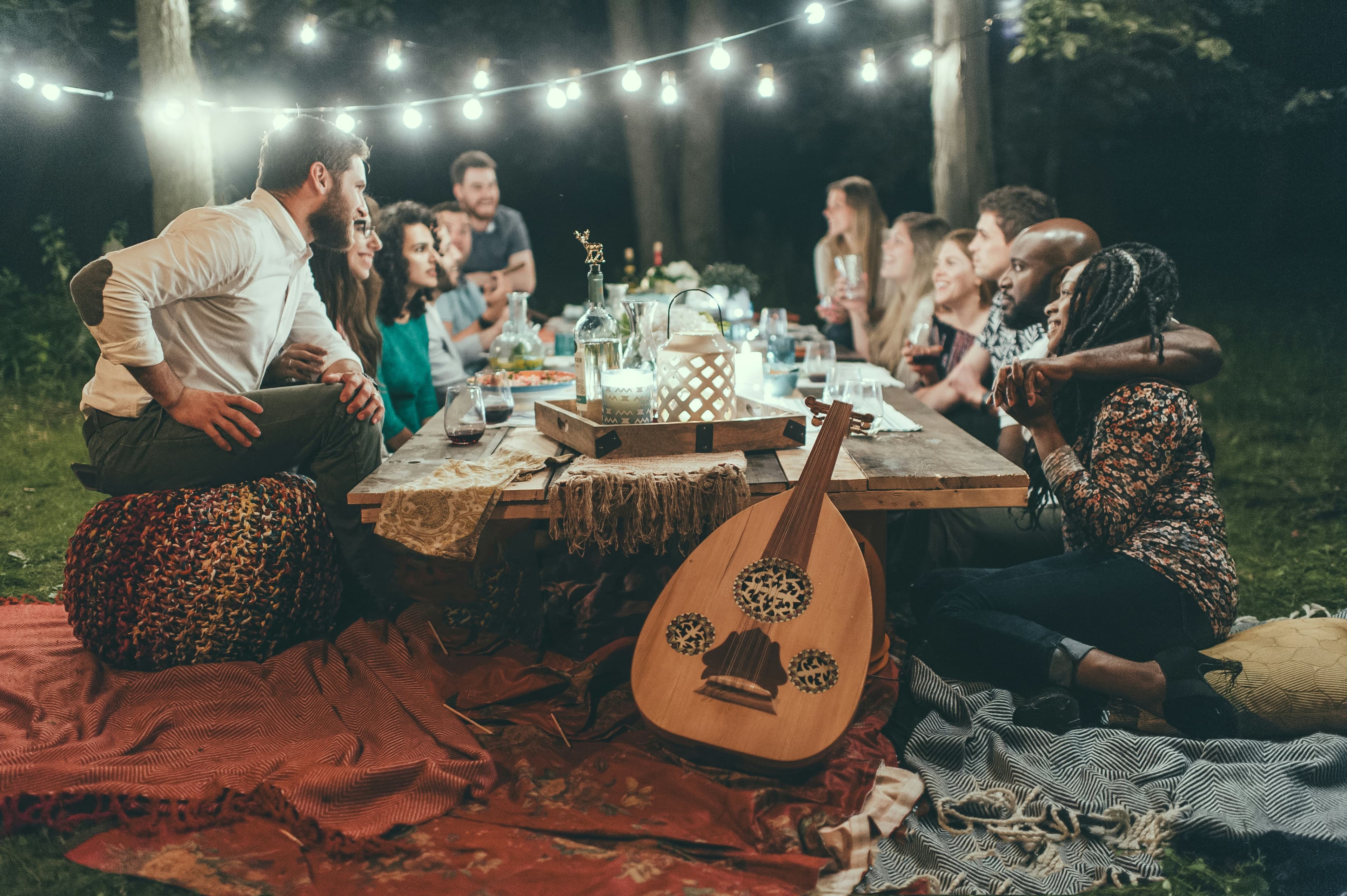 Friends having dinner in a garden lit with string lights